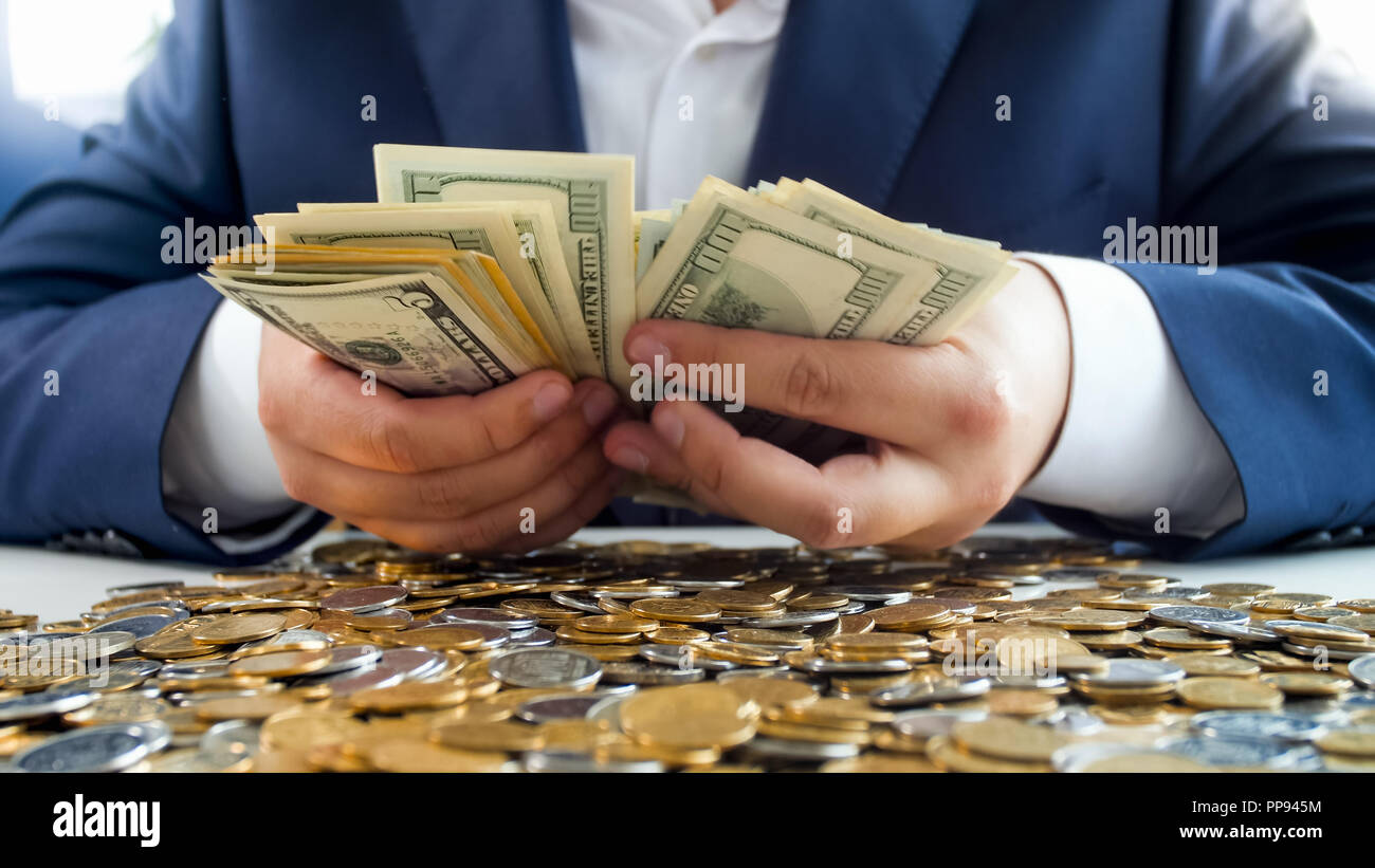 Closeup photo of rich wealthy businessman cointing big stack of money Stock Photo