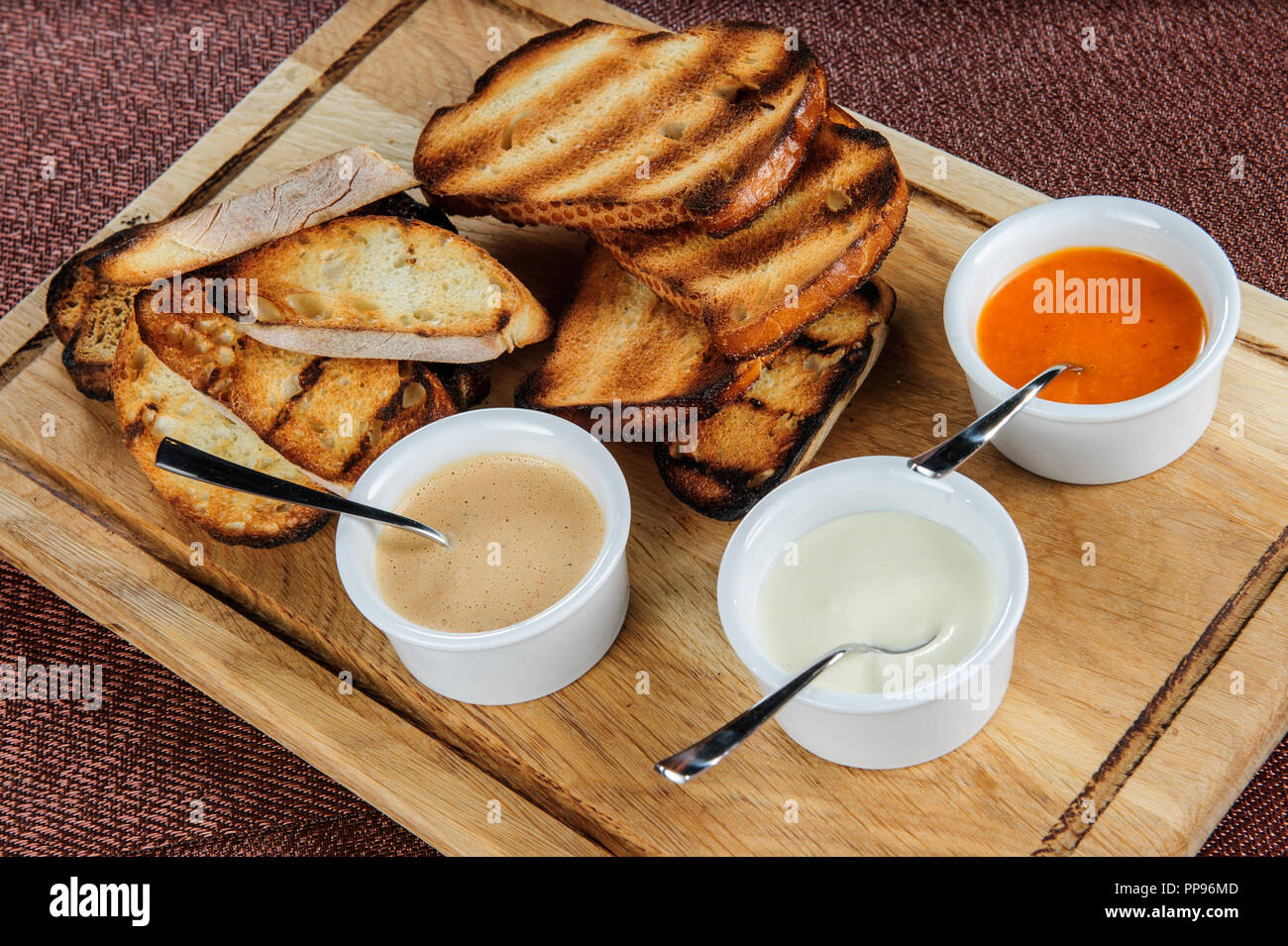 Slice of toast roasted in breaded with cheese and sesame slipped in a sauce on a wooden board Stock Photo