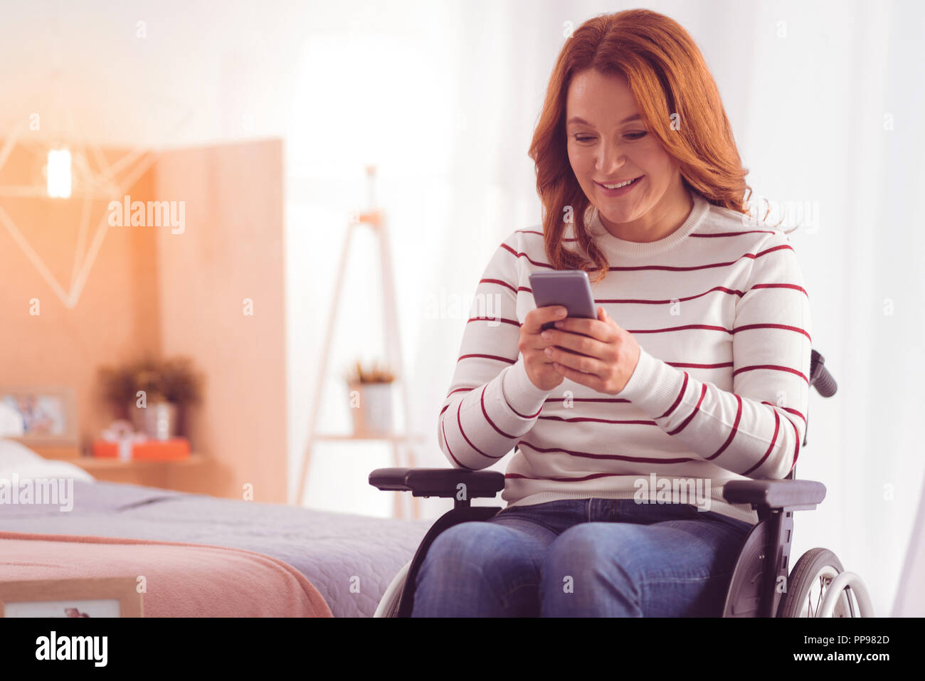 Positive wheelchaired woman using smartphone Stock Photo