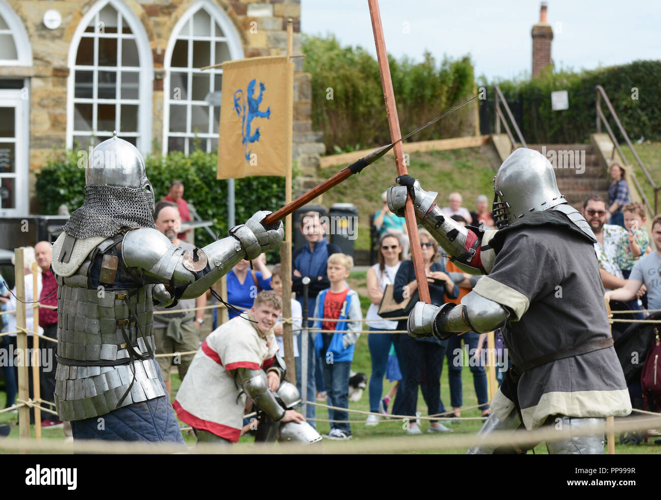 TONBRIDGE, ENGLAND - SEPTEMBER 9, 2018: Combat fighter in medieval body armour strikes his opponent's weapon with a pole arm at Tonbridge Castle Medie Stock Photo