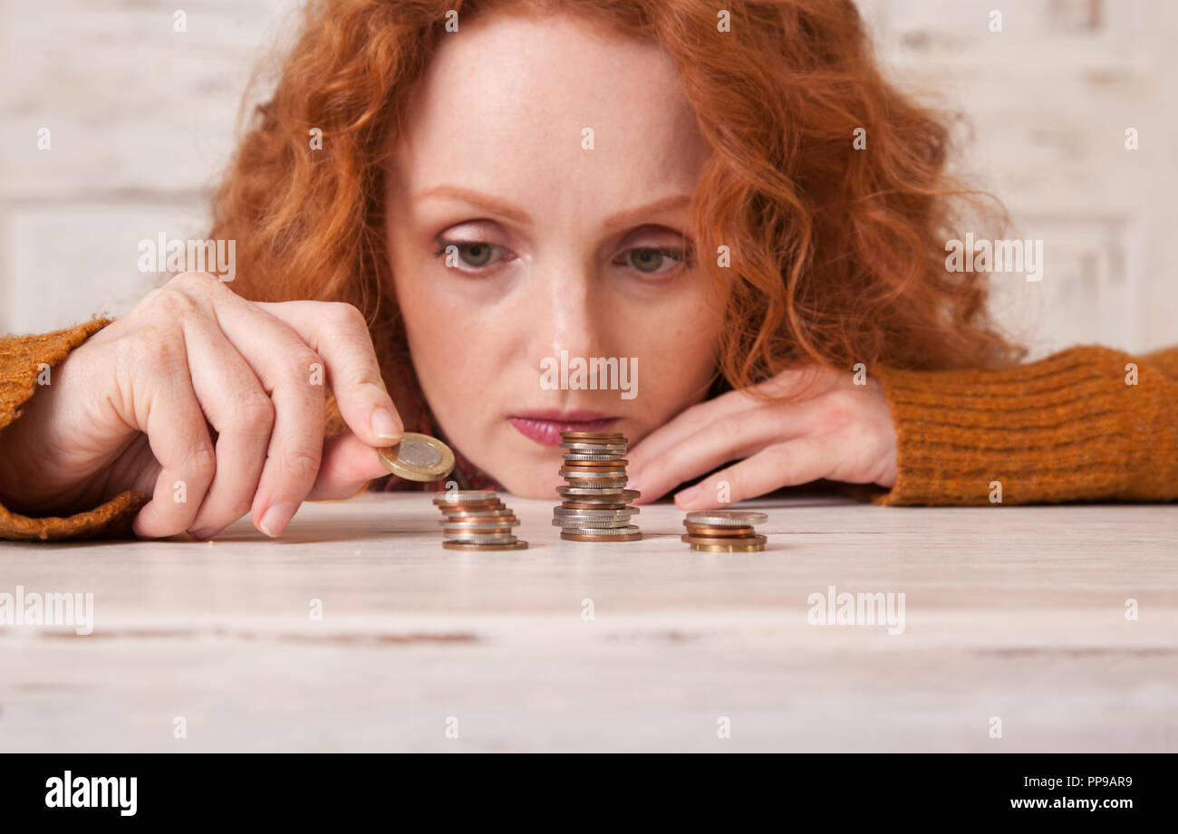 Young woman saving money in stacks of coins Stock Photo