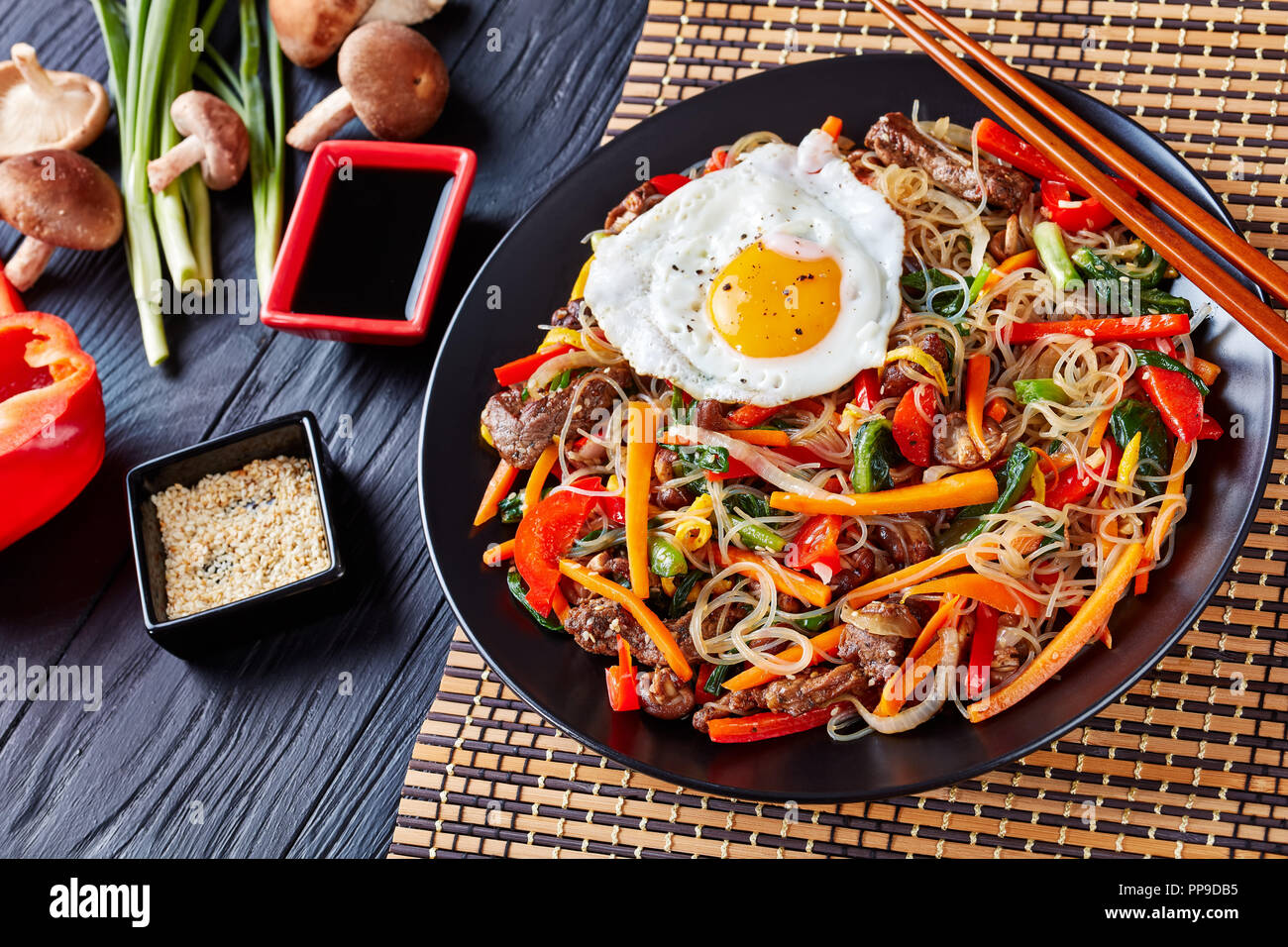 delicious korean dish Japchae: mix of glass noodles, beef and stir fried onion, bell pepper, garlic, spinach, carrot, shiitake mushrooms with sesame s Stock Photo