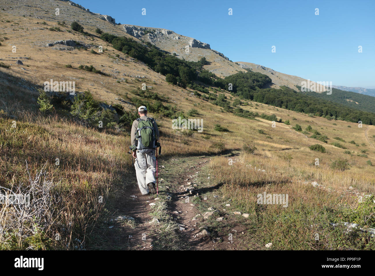 Hiker with backpack and trekking pole on the trail in Crimean mountains, Ukraine Stock Photo