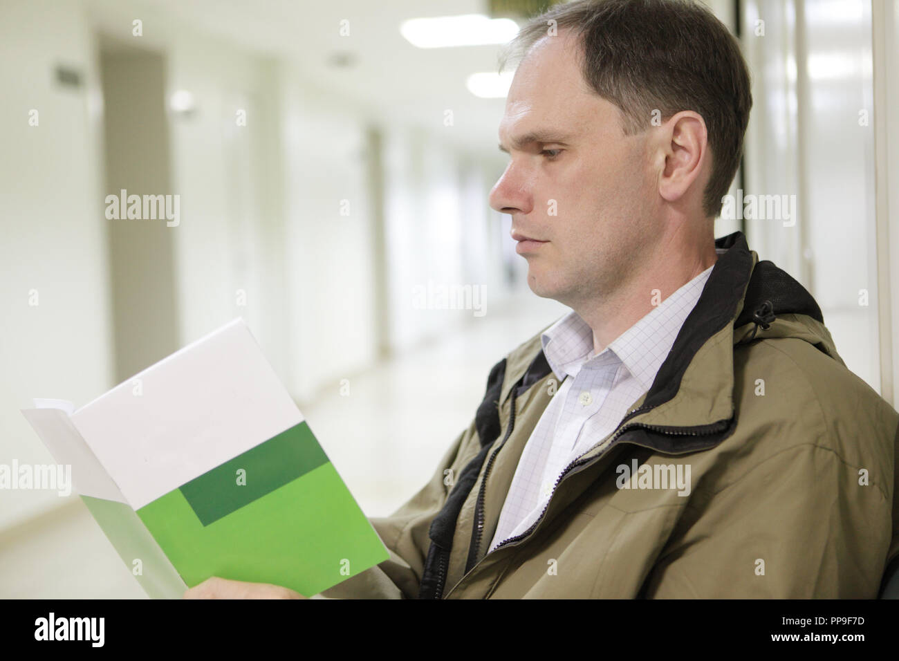 Patient reading health booklet in waiting room of hospital Stock Photo