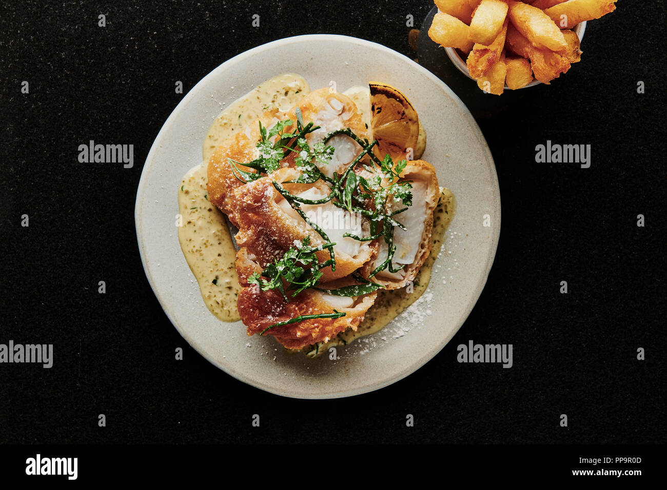 delicious crispy cod fish on white plate with chips in a bowl with