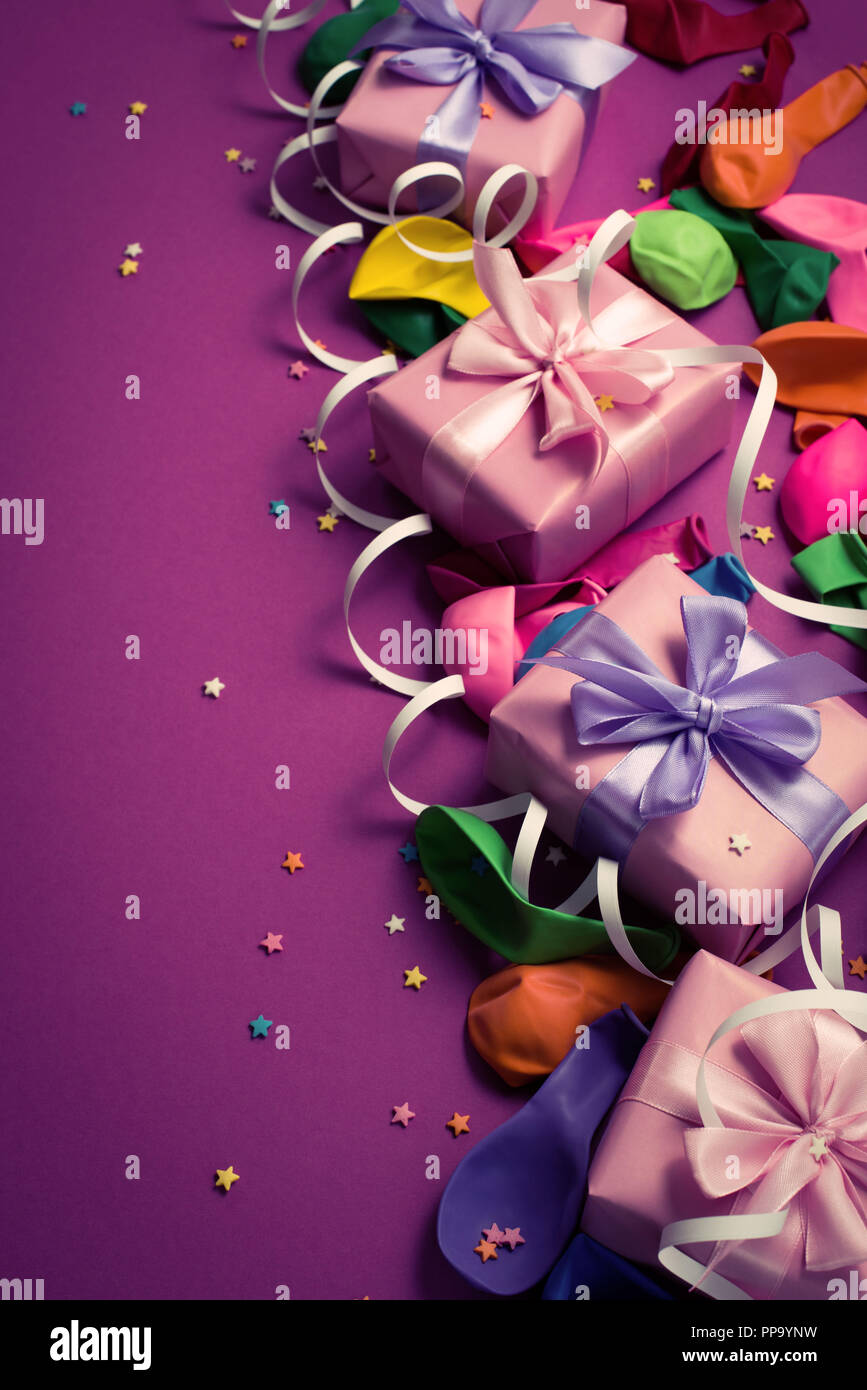Festive background of purple material colorful balloons streamers confetti four boxes gift. Top view flat lay copy space toning Stock Photo