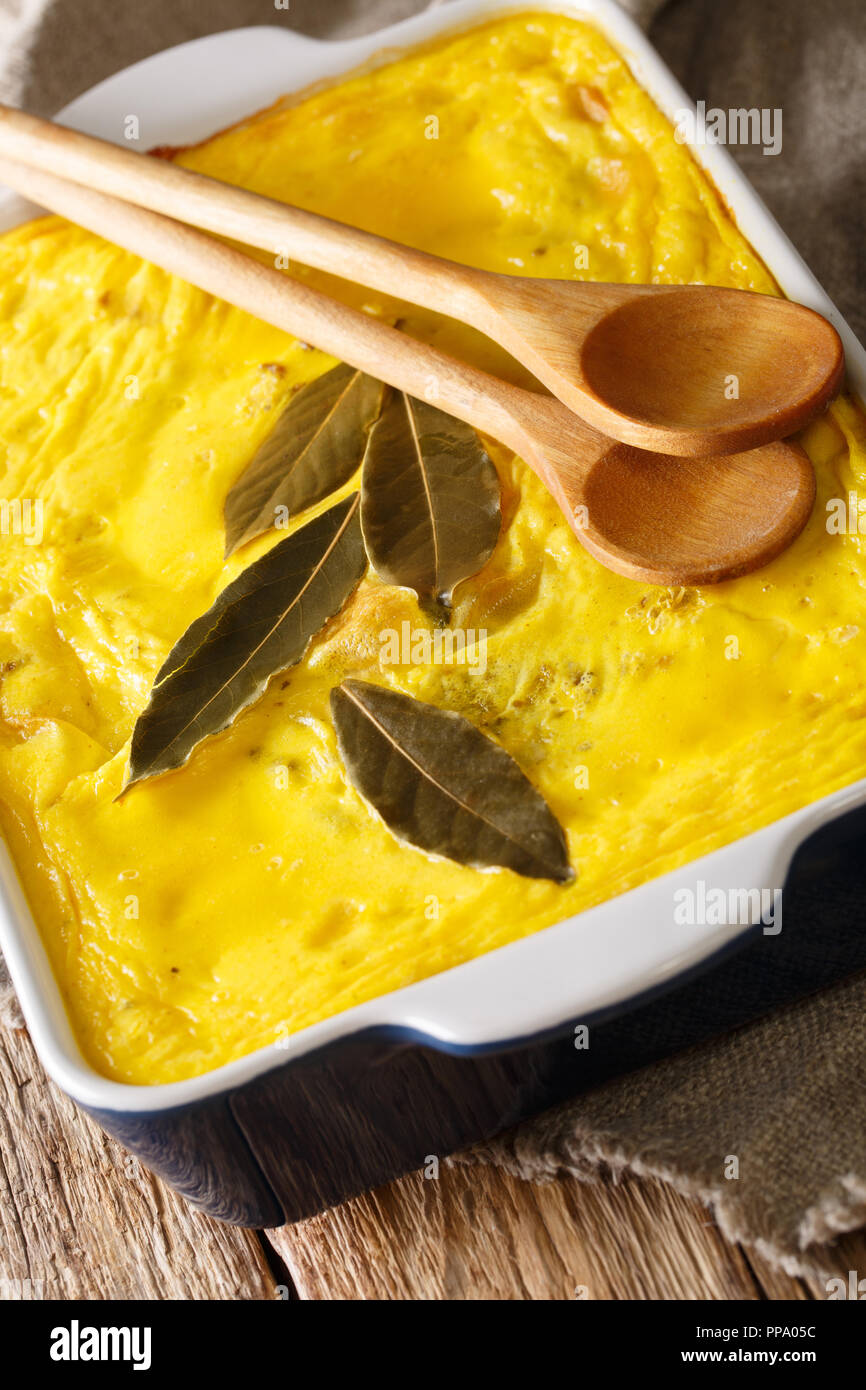 Delicious hot South African food Bobotie spicy minced meat with whipped eggs close-up in a baking dish on the table. vertical Stock Photo