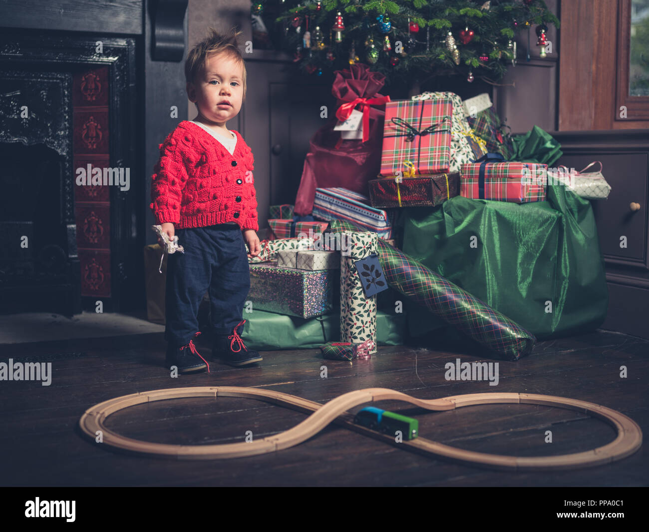 A cute little boy with a wooden train in front of the christmas tree Stock Photo