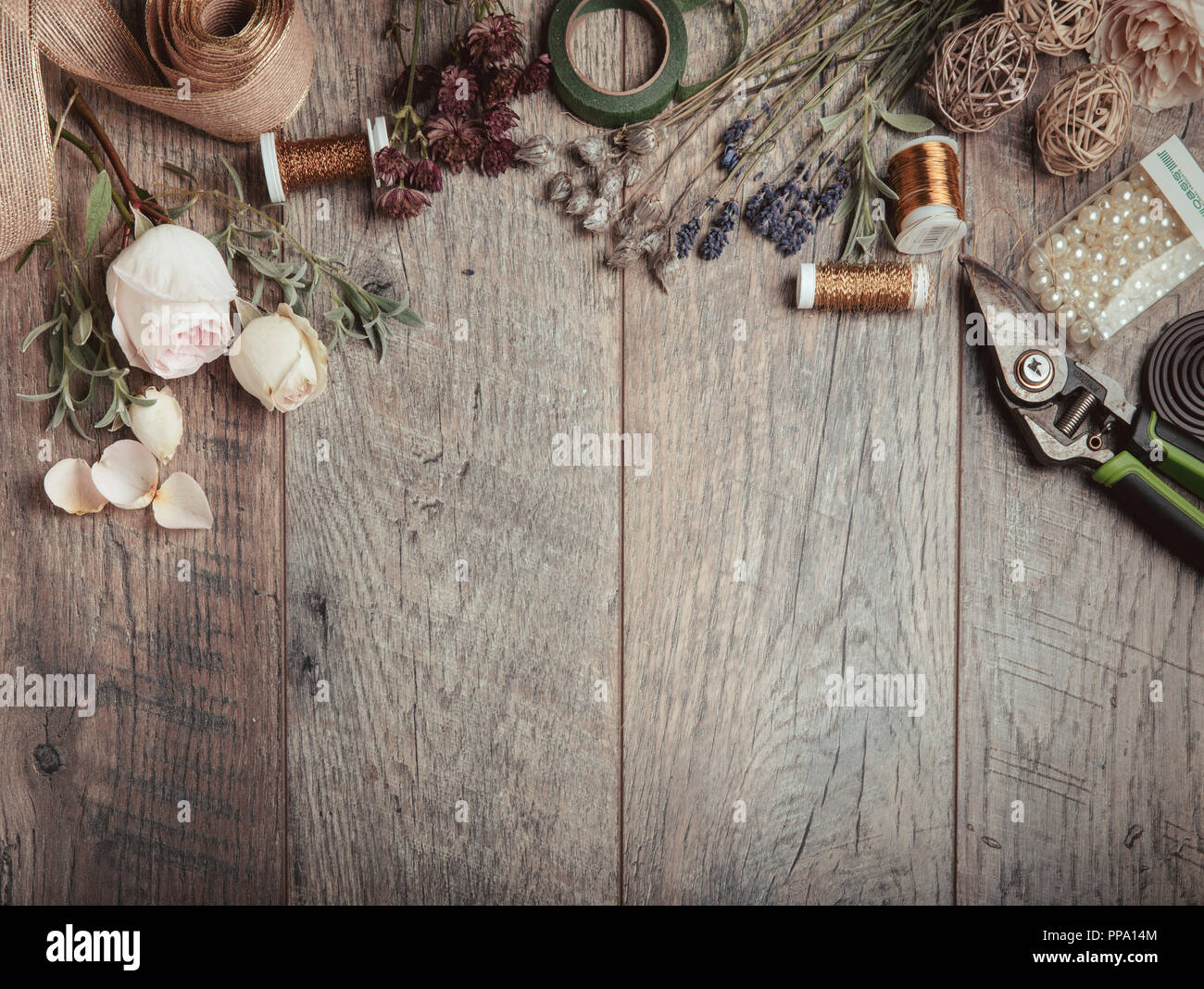 Florist equipment with flowers on wooden background, top view Stock Photo