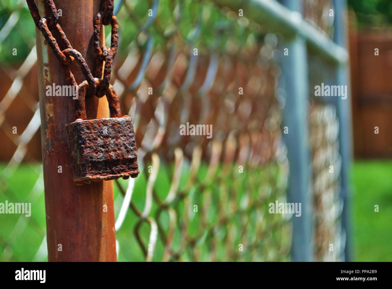 rust covered lock on chain link fence Stock Photo