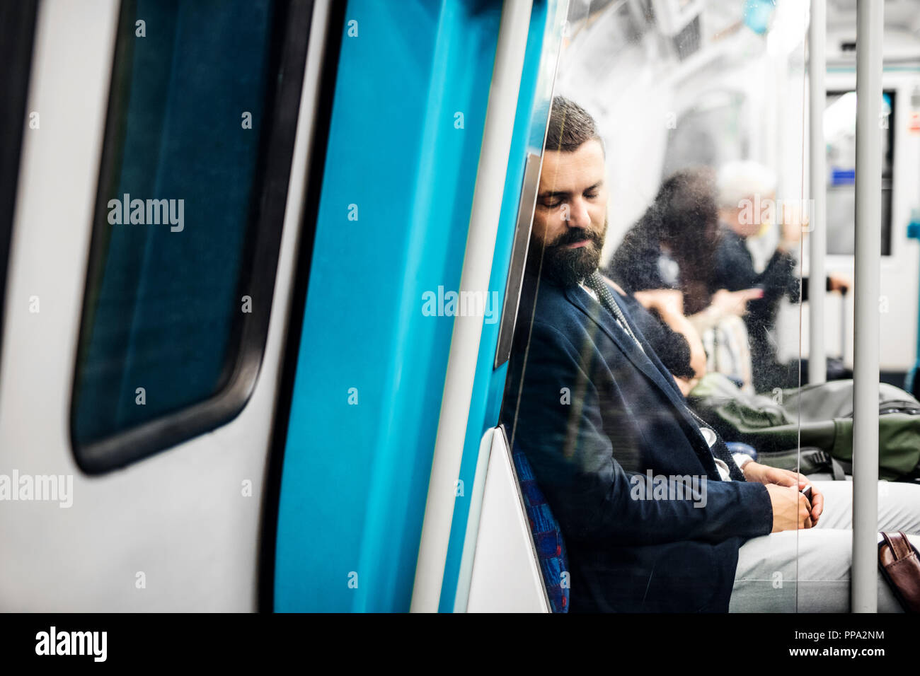 Sleeping hipster businessman inside the subway in the city, travelling to work. Stock Photo
