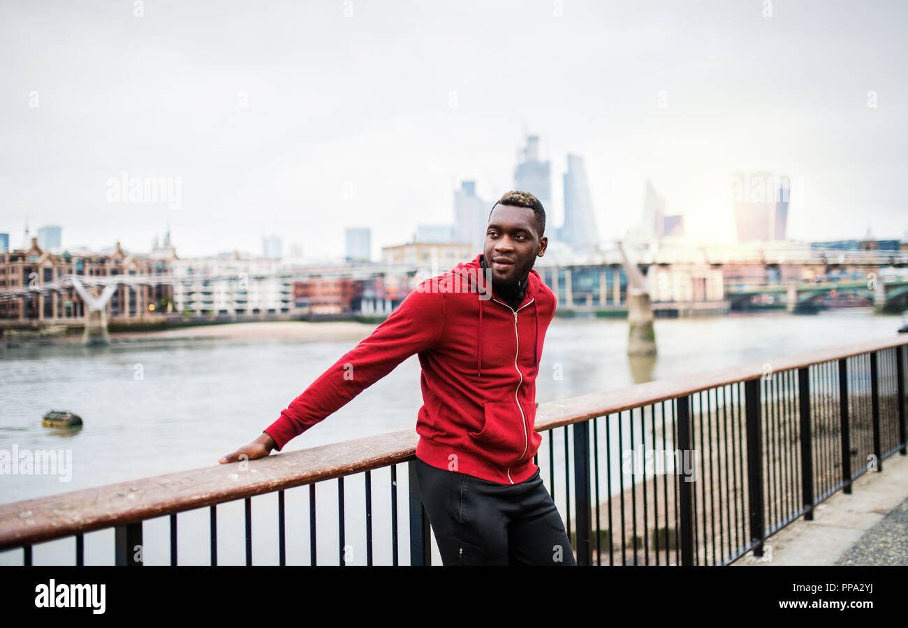 Young sporty black man runner on the bridge outside in a city, resting. Stock Photo