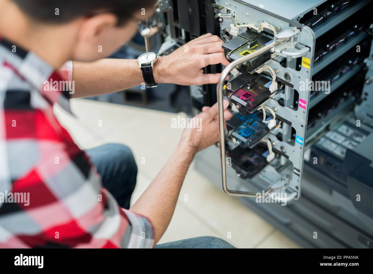 Crop man setting colorful inks in printer Stock Photo