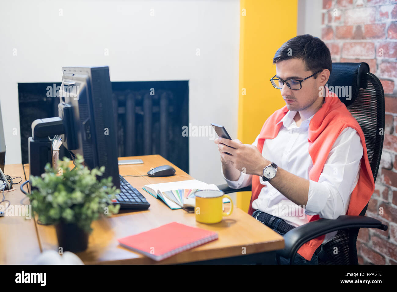 Young designer using phone in office Stock Photo