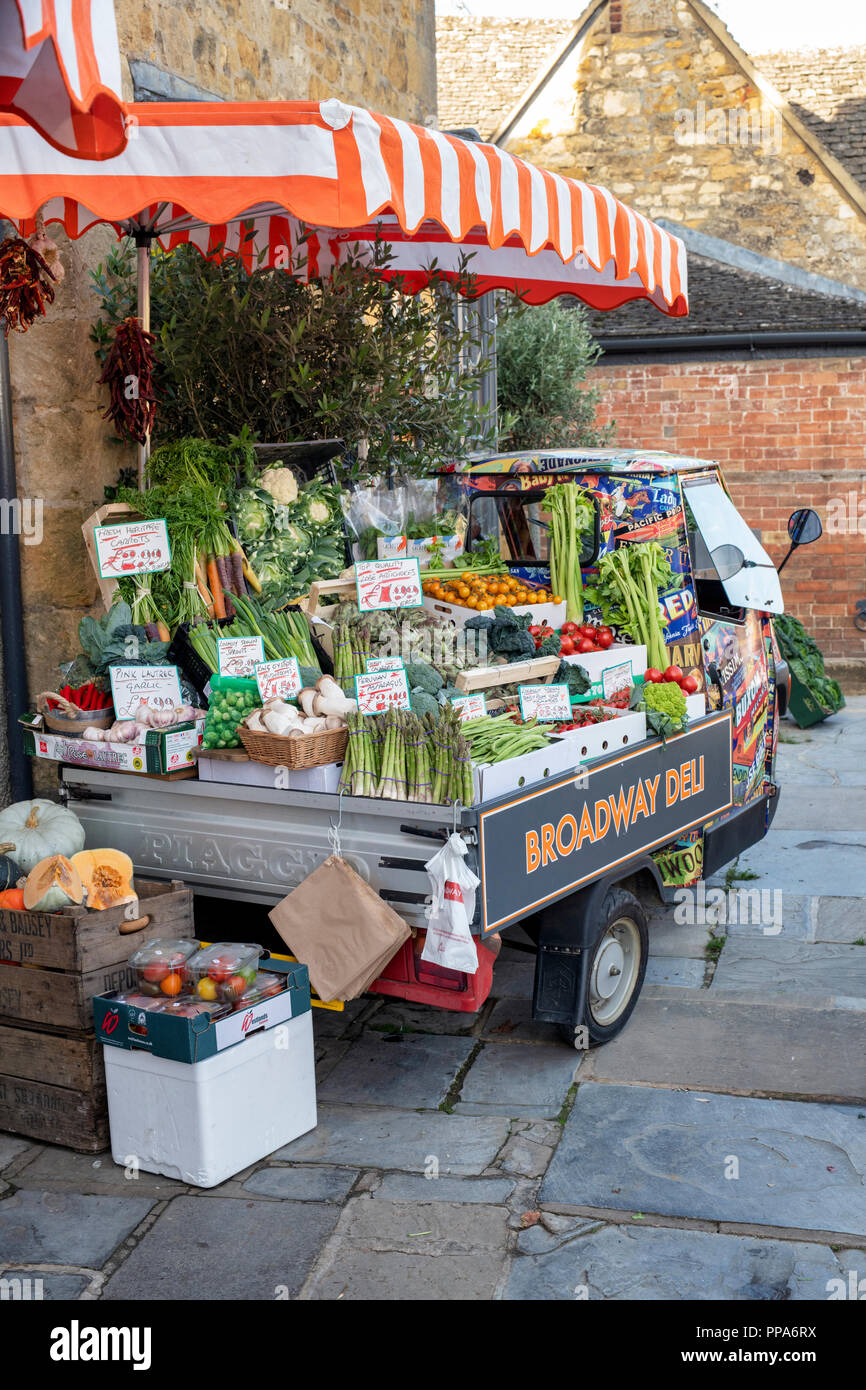 Piaggio ape 50 shop display filled with boxes of vegetables for sale outside the Deli shop, Broadway, Cotswolds, Gloucestershire, England Stock Photo