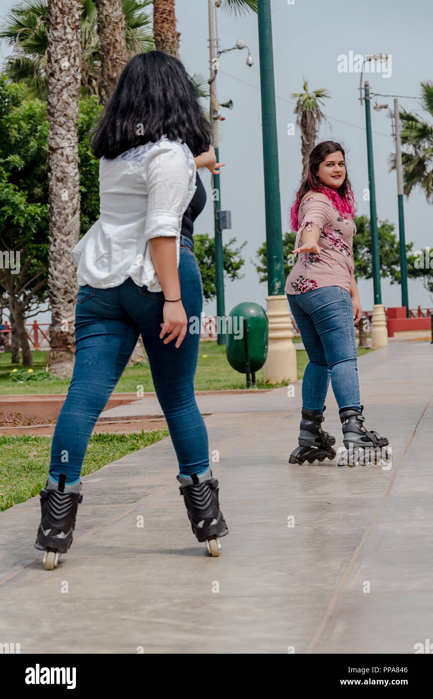 Two chubby girls with inline skates in the park happy Stock Photo