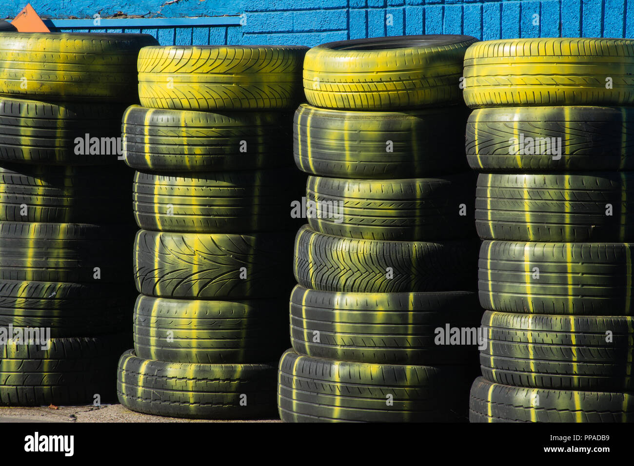 Stacks of old car tyres (tires) with yellow paint on outside a tyre centre Stock Photo
