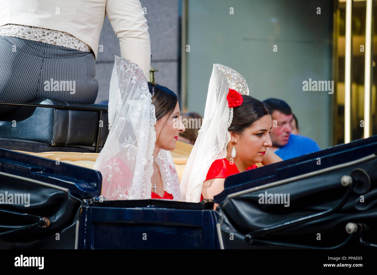 Two spanish women wearing peineta sitting in horse drawn carriage, during equestrian event, Fuengirola, Málaga, Andalusia, Spain. Stock Photo