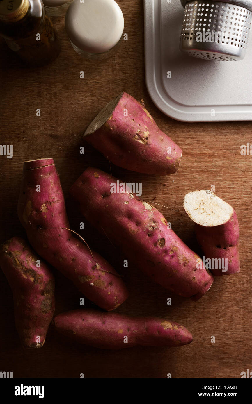 Top view of a bunch of sweet potatoes on a rustic wooden table, waiting to be cooked. Stock Photo