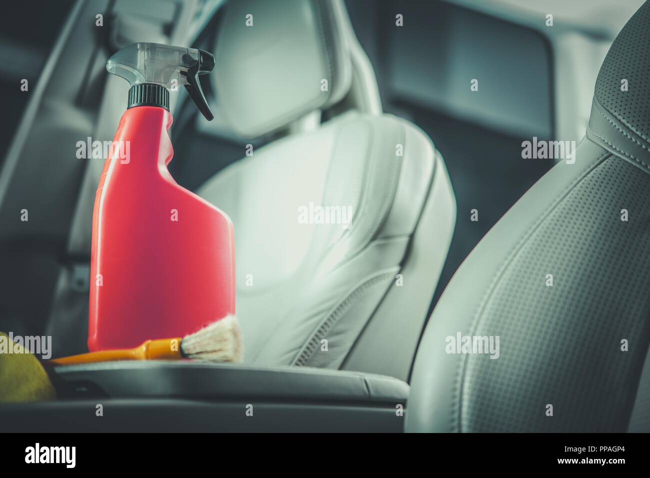 Car Leather Cleaning Detergent in the Orange Red Bottle. Modern Vehicle Interior with Light Leather Finishing. Stock Photo