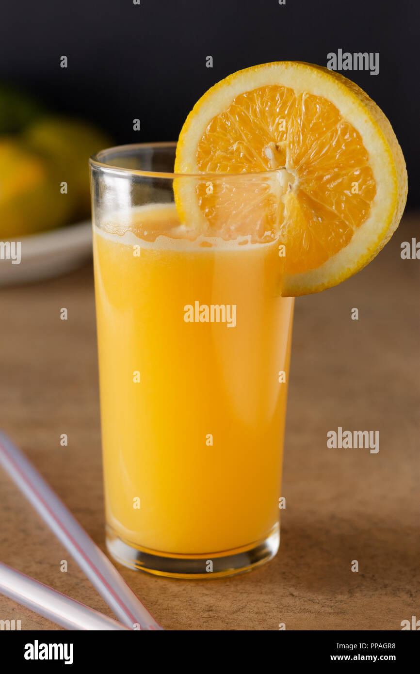 Big glass of orange juice on a wooden table and dark background. Stock Photo