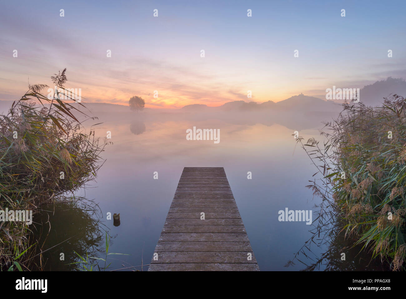 Wooden Jetty with Reflective Sky in Lake at Dawn, Drei Gleichen, Ilm District, Thuringia, Germany Stock Photo