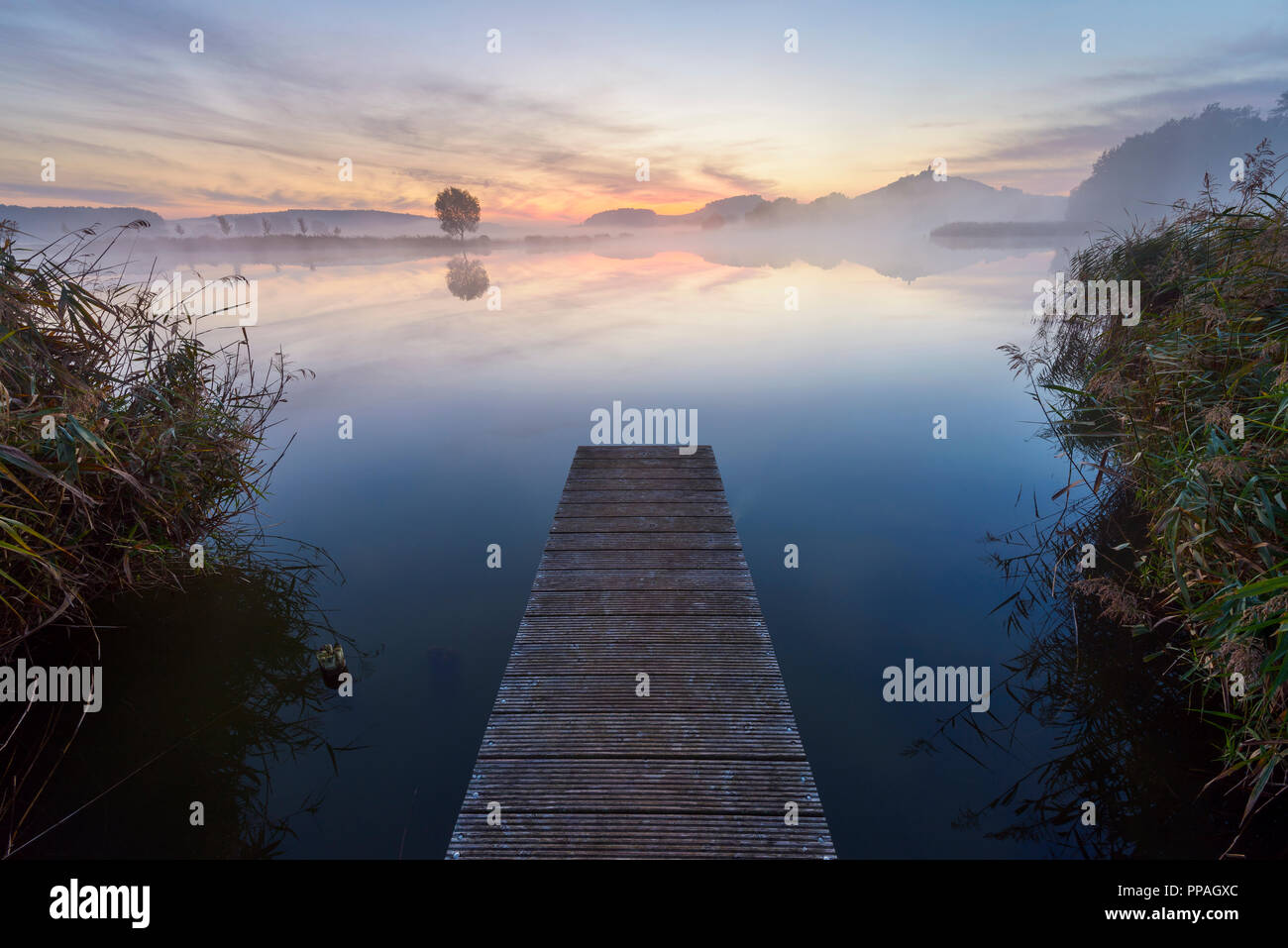 Wooden Jetty with Reflective Sky in Lake at Dawn, Drei Gleichen, Ilm District, Thuringia, Germany Stock Photo