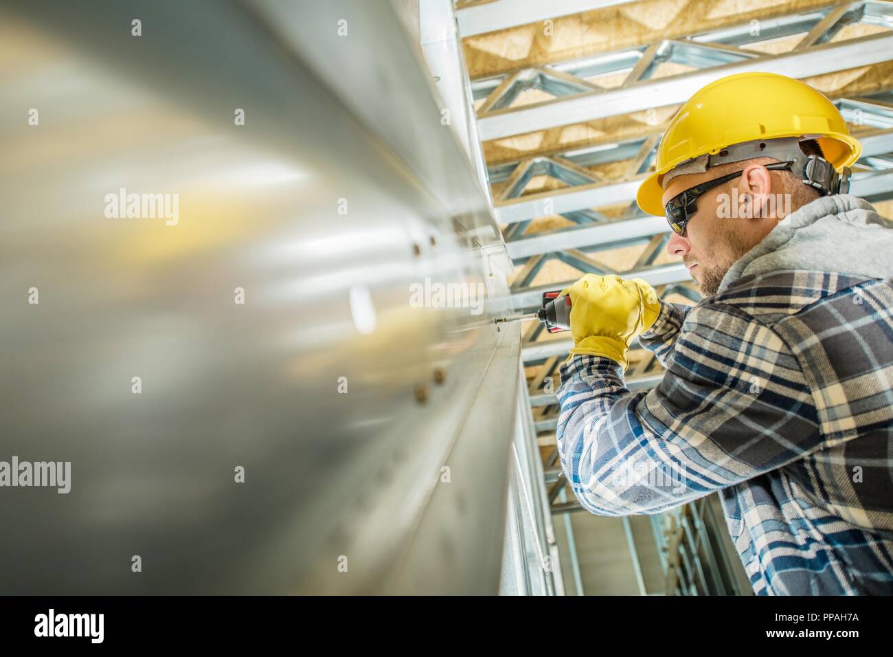 Building Steel Frame Contractor Worker Closeup Photo. Caucasian Men with Drill Driver Connecting Steel Elements of the Frame. Stock Photo