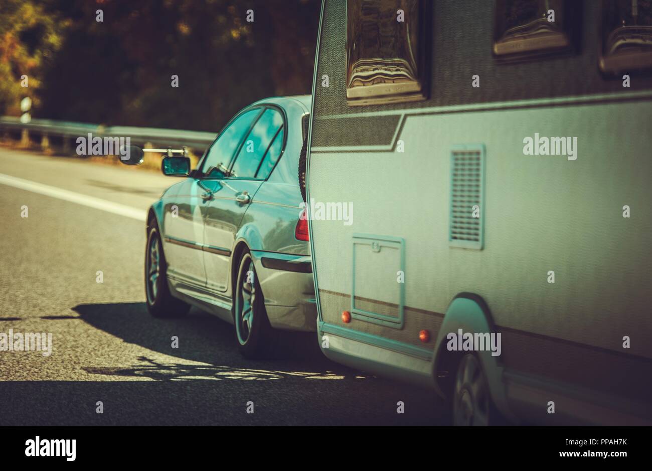 Compact Car with Travel Trailer on the Highway. Vacation Road Trip. Recreational Vehicle. Stock Photo