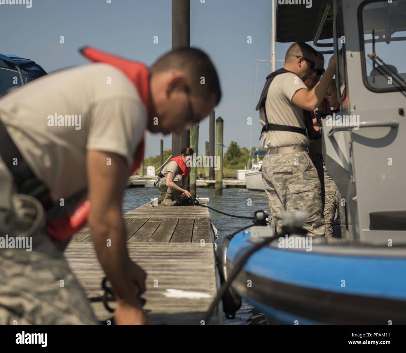 U.S. Air Force Airmen assigned to the 633rd Security Forces Squadron perform boat-docking procedures at Joint Base Langley-Eustis, Virginia, Aug. 14, 2018. During the course, the SFS members learned the fundamentals of boat operations including docking and tying knots. Stock Photo