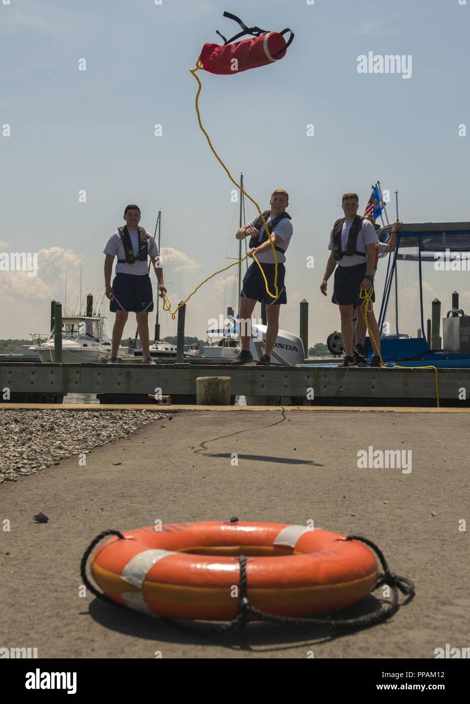 U.S. Air Force Airmen assigned to the 633rd Security Forces Squadron toss a rope at Joint Base Langley-Eustis, Virginia, Aug. 15, 2018. During the Boat Operations and Training course participants practiced proper rescue techniques on land before performing the techniques on a vessel. Stock Photo