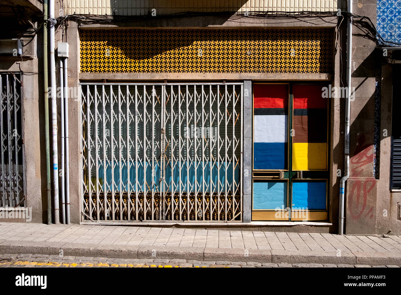 facade of an old and abandoned store with colorful Portuguese tiles and super colorful door inspired the Mondrian paints and pictures. Stock Photo