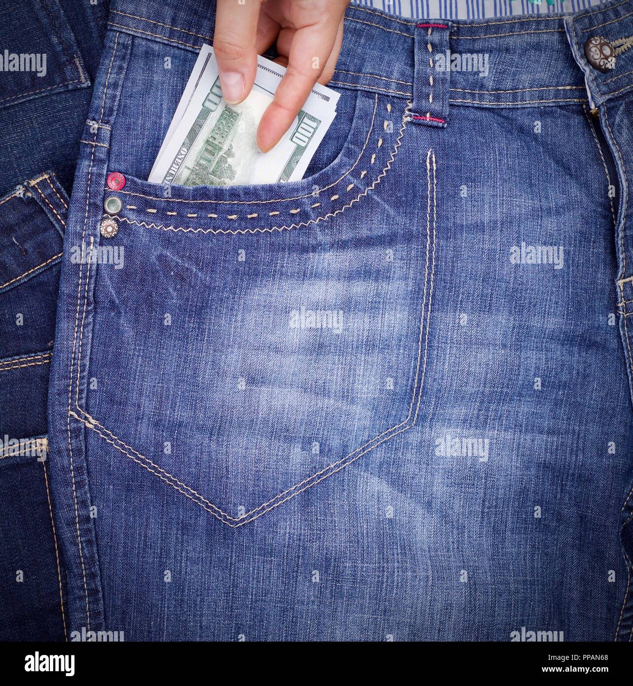 human hand sticks them front pocket of blue jeans paper money dollars