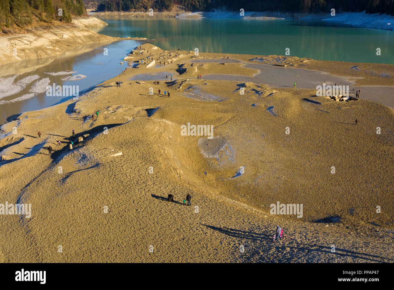 Deflated storage lake with tourists in winter, Sylvenstein Lake, Isartal, Lenggries, Upper Bavaria, Bavaria, Germany, Europe Stock Photo