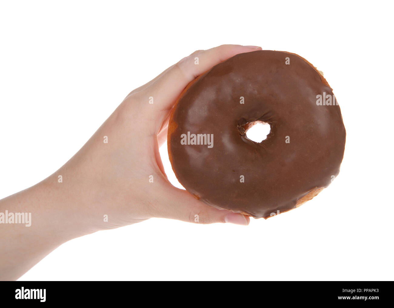 Young hand holding one chocolate glazed round donut isolated on white background. Stock Photo