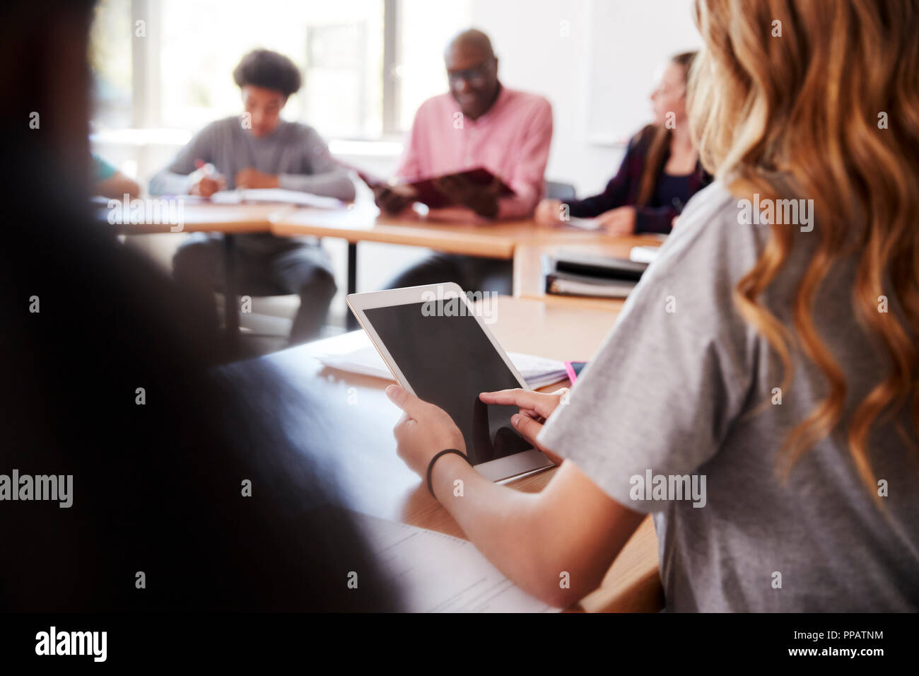 Female High School Student Using Digital Tablet Whilst Sitting At Desk In Class Stock Photo