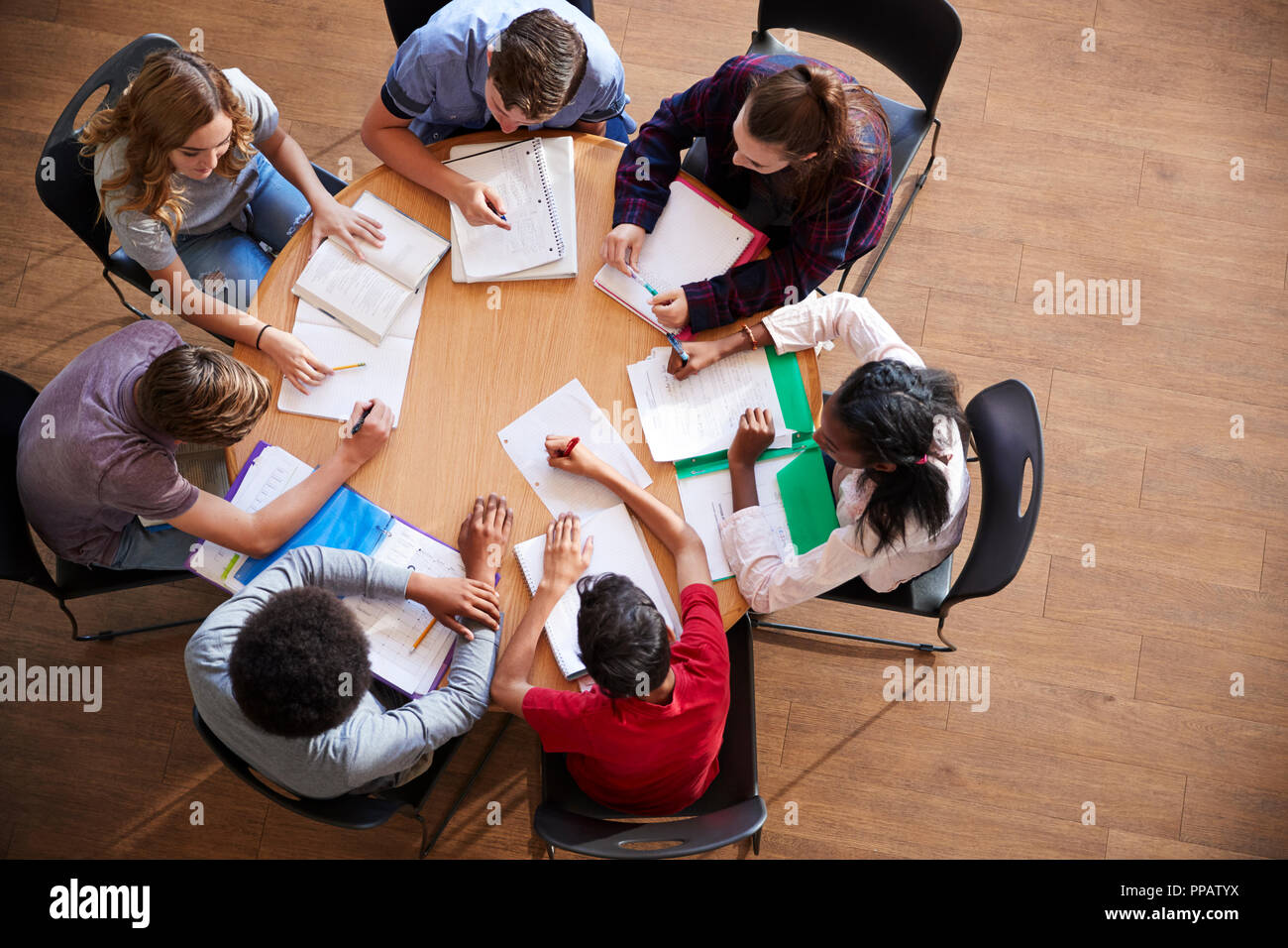 Overhead Shot Of High School Pupils In Group Study Around Tables Stock Photo