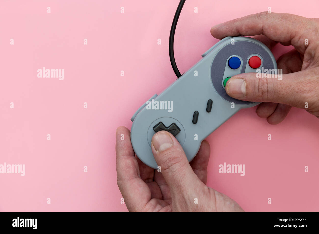 Man playing video game with controller on pink background Stock Photo