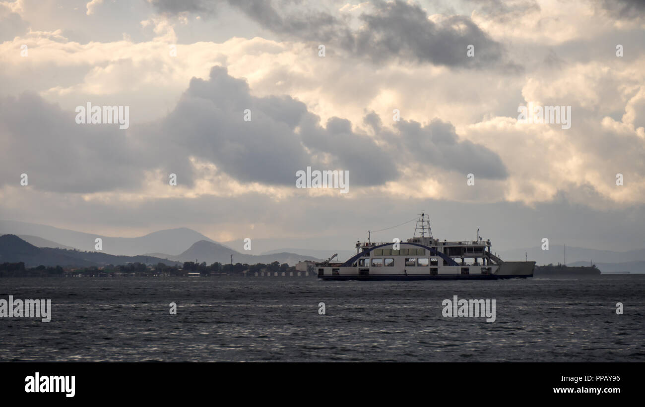 A ferry boat is navigating in the sea in front of the turkish city of Izmir, Turkey, during the fluffy cloudy sky Stock Photo