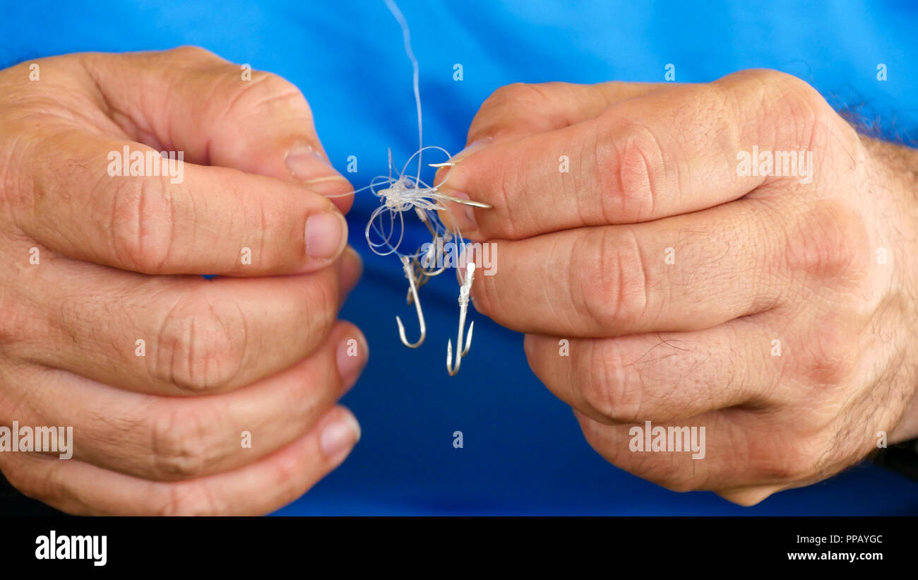 Man unraveling to the tangled and knotted Fishing line. Problem solving. Stock Photo