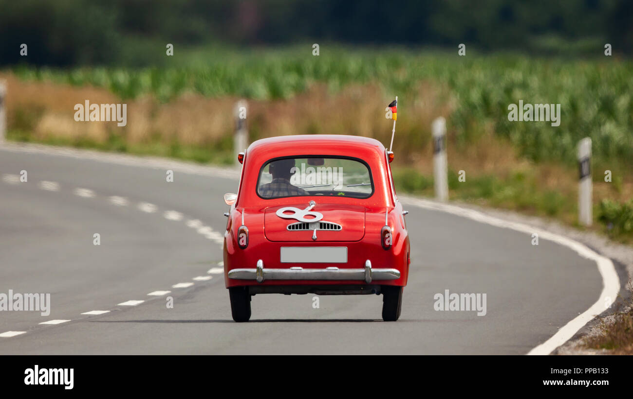 Red vintage micro car 'Gogomobil' in compressed tele view on country road Stock Photo