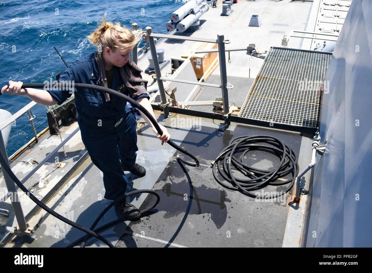 ARABIAN GULF (Aug. 13, 2018) Gas Turbine Systems Technician (Mechanical) 3rd Class Jillian Storey coils a hose after conducting a 72-hour gas turbine engine intake cleaning on the Arleigh-burke class missile-destroyer USS The Sullivans (DDG 68). The Sullivans is deployed to the U.S. 5th Fleet area of operations in support of naval operations to ensure maritime stability and security in the Central region, connecting the Mediterranean and the Pacific through the western Indian Ocean and three strategic choke points. Stock Photo