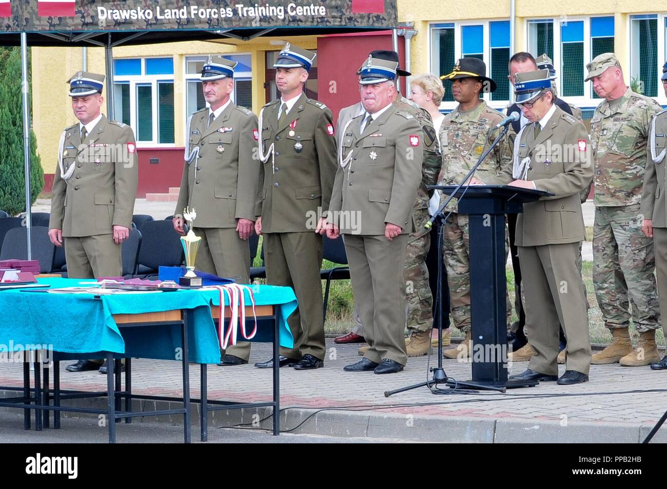 A command team for 2nd Battalion, 8th Cavalry Regiment, 1st Armored Brigade Combat Team, 1st Cavalry Division, Polish soldiers and civilians, stands during a ceremony honoring currently serving Polish soldiers, veterans and the deceased, in Drawsko Pomorskie Training Area, Poland, Aug. 14, 2018. Soldiers from 1st ABCT are deployed across Europe in support of Atlantic Resolve, a demonstration to NATO allies and the world of continued commitment to peace, security and stability in Europe. Stock Photo