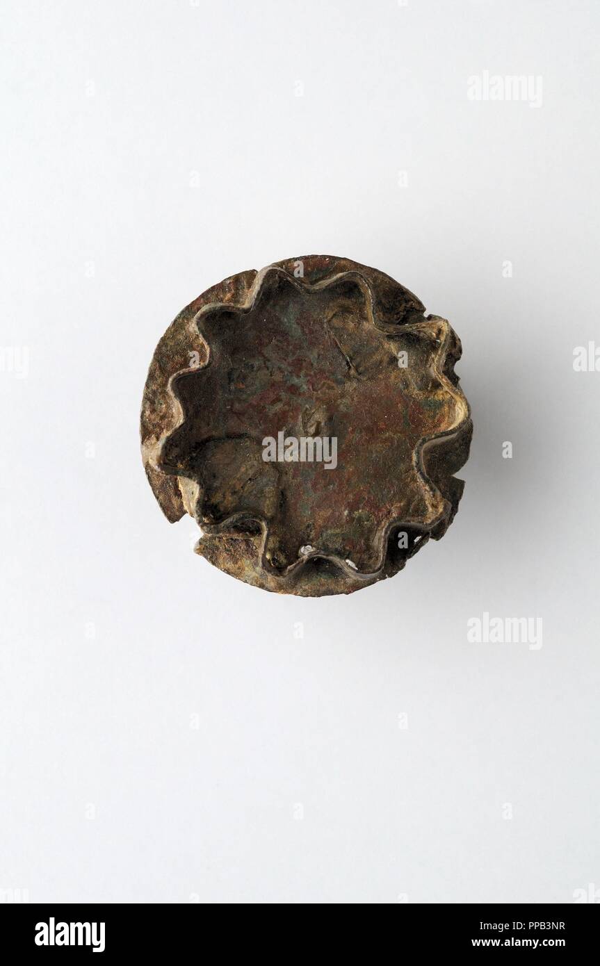 Discoidal fibula of bronze, which would be topped with a mosaic of small pieces of glass or semiprecious stones. Diameter 30mm Width 18mm Thickness 1mm (6 th CE ) - Visigoth period, from the "Afflicted Necropolis " - Archaeological site of Complutum in Alcalá de Henares ( Madrid ). SPAIN. Stock Photo
