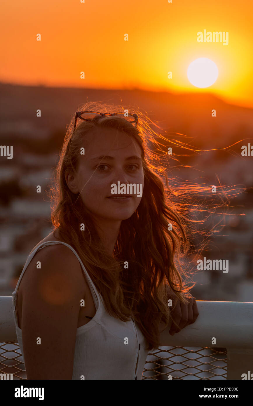 Young woman with white top smiles, backlit at sunset, Plaza de la Encarnacion, behind houses, Sevilla, Andalucia, Spain Stock Photo