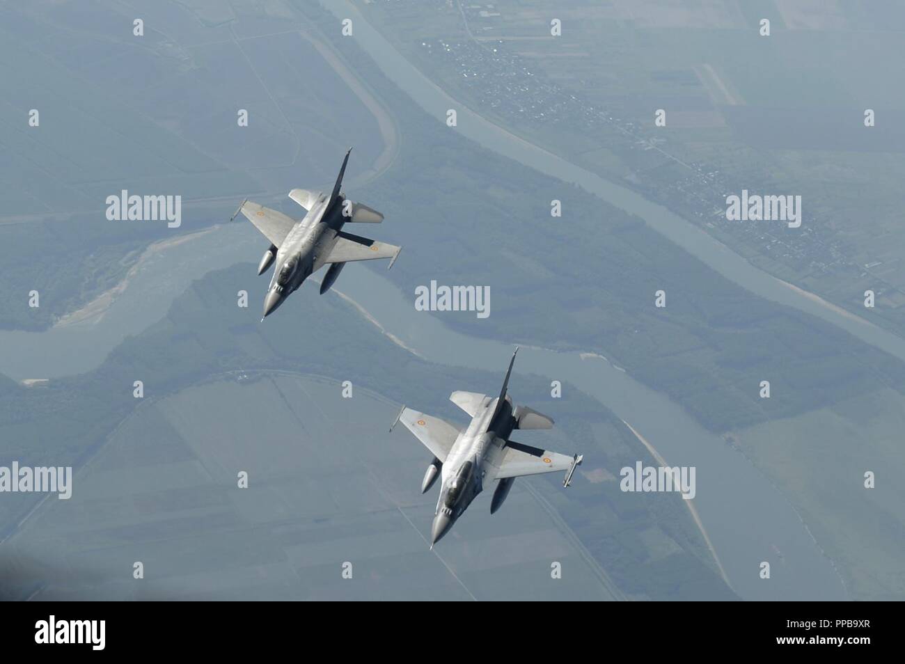 Two Romanian F-16 Fighting Falcons fly below a U.S. Air Force KC-135R Stratotanker assigned to the 100th Air Refueling Wing, Royal Air Force Mildenhall, England, above Bucharest, Romania, Aug. 20, 2018. The U.S. works closely with Romania on a range of global challenges, including promoting international peace, security and economic prosperity. Stock Photo