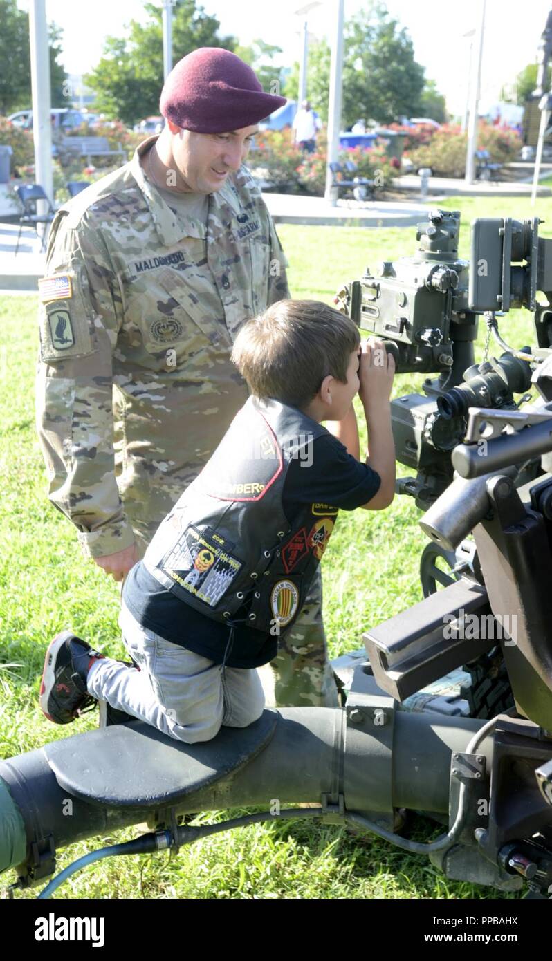 A U.S. Army Paratrooper assigned to the 82nd Airborne Division demonstrates the use of artillery equipment to a guest of the National Airborne Day celebration at the Airborne and Special Operations Museum in downtown Fayetteville, North Carolina, Aug. 18, 2018. Attendees of the event received hands on experience with a variety of equipment currently used by the U.S. Army. Stock Photo