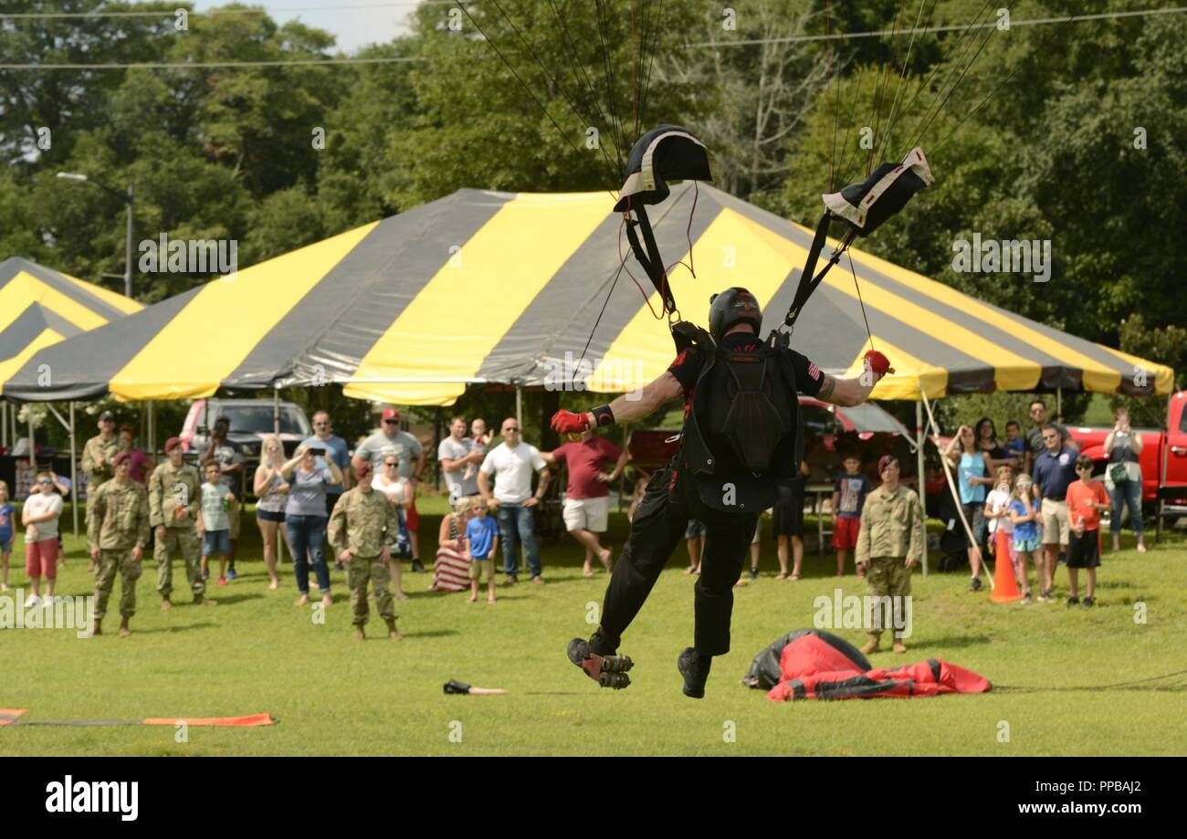 A member of the U.S. Army Special Operations Command Black Daggers parachute demonstration team parachutes onto the Airborne and Special Operations Museum grounds to close out the National Airborne Day celebration in downtown Fayetteville, North Carolina, Aug. 18, 2018. Congress designated National Airborne Day in 1991 to honor the first parachute jump of the U.S. Army Parachute Test Platoon on Aug. 16, 1940 as well as past and present Paratroopers. Stock Photo