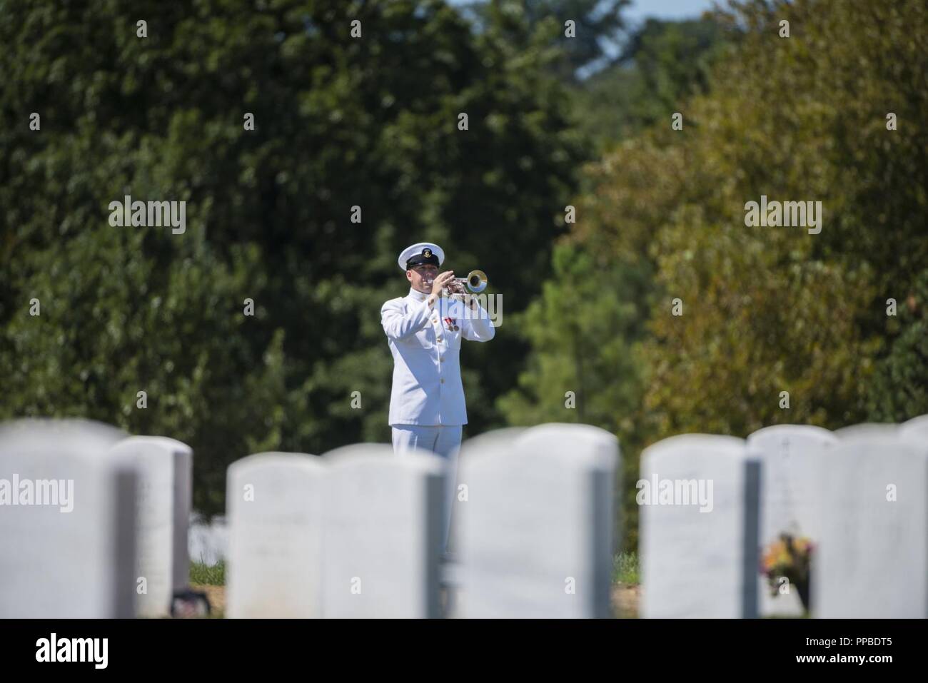 U.S Navy Musician 1st Class Ethan Bartley from The U.S. Navy Band plays Taps during the full honors funeral of U.S. Navy Lt. Commander William Liebenow in Section 62 of Arlington National Cemetery, Arlington, Virginia, August 23, 2018. On August 7, 1943, Liebenow skippered a patrol torpedo boat to rescue the sailors of PT-109 who had survived several days on inhospitable islands after a Japanese destroyer had rammed their boat, killing two crewmen. Among those rescued was Liebenow’s bunkmate, John F. Kennedy, then 26. For his acts of heroism during World War II, he received the Bronze and Silv Stock Photo
