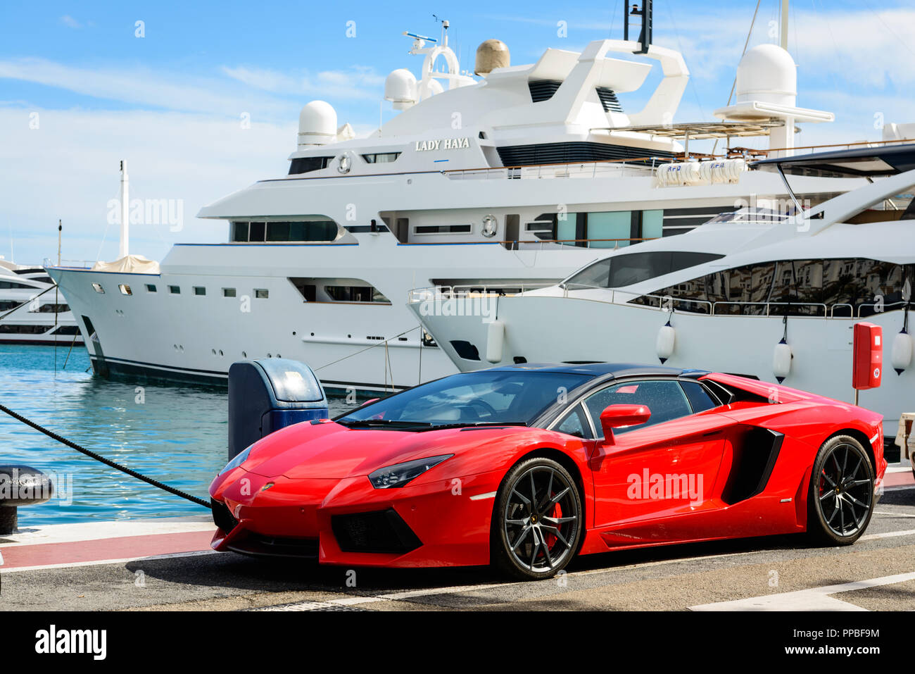 Sports cars parked next to yachts in the Luxury marina of Puerto